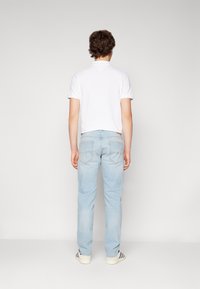 Weißes Kurzarm-T-Shirt, hellblaue Jeans, lässige gestreifte Schuhe; einfarbiger Stoff, schmaler Schnitt, schlichtes Design, standardmäßige Rückansicht.