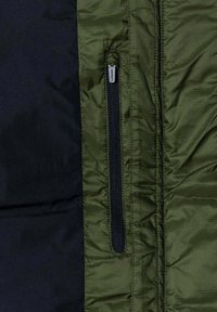 Zielono-czarna izolowana kurtka o gładkiej teksturze, z pionową kieszenią na zamek błyskawiczny i subtelnym wzorem w paski na zielonym materiale.