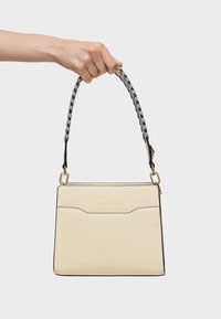 Beżowa skórzana torebka o zdefiniowanym kształcie, z wytłoczonym logo oraz plecionym paskiem z szarymi i czarnymi akcentami. Widoczne złote dodatki.