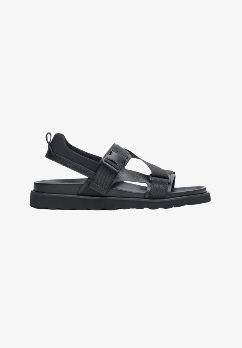 Zwarte sandaal met een platte zool, verstelbare banden en een gehamerde afwerking. Gemaakt van synthetische materialen met een lus aan de hiel.