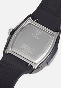 Bracelet de montre en caoutchouc noir avec un fond en acier inoxydable. Boîtier carré avec des accents en ton argenté. Résistant à l'eau jusqu'à 50 mètres.