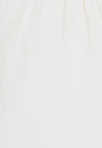 Vit klänning i tyg med en strukturerad, prickig design och vertikala ränder. Lätt material med en mjuk yta.