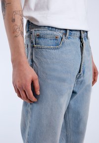 Ljusblå denimjeans med avslappnad passform, med fem fickor, synlig sömnad och detaljer i koppar.