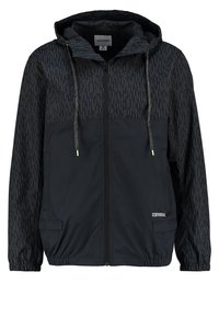 Svart vindjacka med huva, zip-stängning, två framfickor och ett texturerat mönster på ärmarna. Elastisk nederkant för justering av passformen.