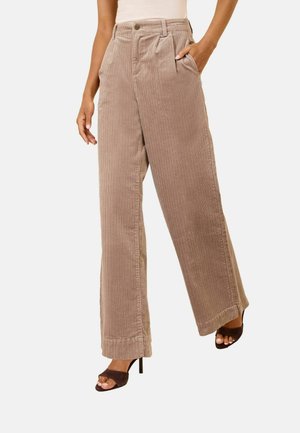 Woman wearing beige wide-leg corduroy pants with front pleats and side pockets, paired with dark brown open-toe high heel sandals.