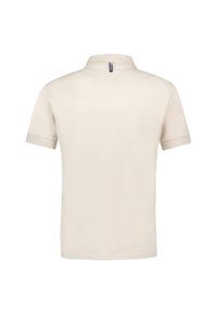 Camisa polo de color crema de mangas cortas con cuello alzado, que presenta una pequeña cremallera en la parte trasera y textura lisa.