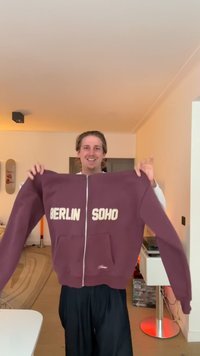 Maroon zip-up hoodie featuring "BERLIN" and "SOHO" in cream text. Soft fabric, full sleeves, front pockets, and elastic cuffs.
