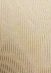 Beiger gerippter Stoff mit vertikalen Linien, weichem Textur und einem dezente Glanz. Das Material wirkt leicht und dehnbar.