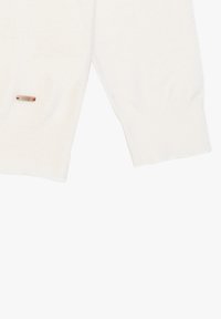 Maglione bianco realizzato in morbido tessuto, caratterizzato da maniche lunghe, orlo a costine e una piccola etichetta decorativa sul lato inferiore.