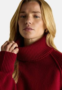 Punane soonikkoe kaelusega sviiter, millel on pikad varrukad ja mugav lõige. Sujuv tekstuur, minimalistlik disain.