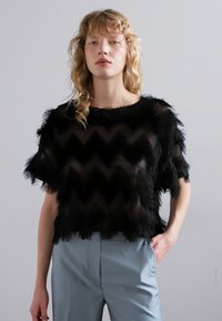 Must must või musta varjundiga poolläbipaistev pluus, millel on sogaseline muster, millel on suleline tekstuur ja lühikesed varrukad. Komplekteeritud helesiniste pükstega.