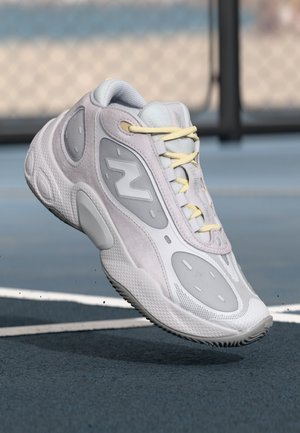 Light gray athletic shoe with a textured mesh upper, soft suede accents, yellow laces, and a distinctive N logo on the side.
