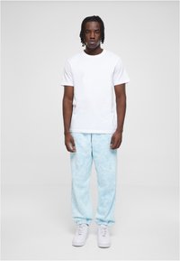 Hvit bomull t-skjorte kombinert med lys blå tie-dye joggebukser, med elastisk midje og ribbestrikkede mansjetter. Hvite sneakers fullfører antrekket.