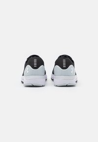 Chaussures de sport noires avec un dessus texturé, semelle blanche et accents de talon gris. Détails réfléchissants pour améliorer la visibilité. Conception légère.
