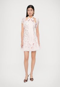 Krátke ružové šaty s kvetinovou výšivkou, priesvitnými nafúknutými rukávmi a mašľou pri výstrihu. Tylová sukňa pridáva štruktúru; doplnené lodičkami na podpätku.