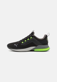 Black athletic shoes made of mesh and rubber, featuring green accents, a padded collar, and a visible air cushion in the sole.