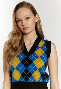 Pulover tricotat cu decolteu în V, având un model în romburi albastre, galbene și negre, accentuat de linii albe și o margine rib knit neagră.
