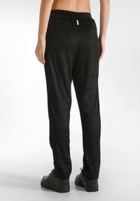 Zwarte corduroy broek met een ribbelstructuur, een elastische tailleband en een relaxte pasvorm. Voorzien van een gladde afwerking en zijzakken.