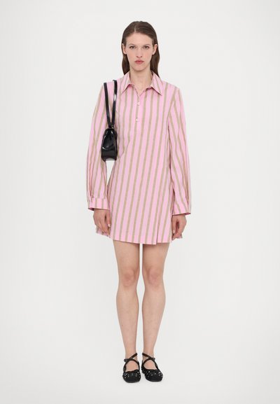Pink and gold striped long-sleeve shirt dress with a collar, button placket, and black handbag; worn with black shoes and flat design.