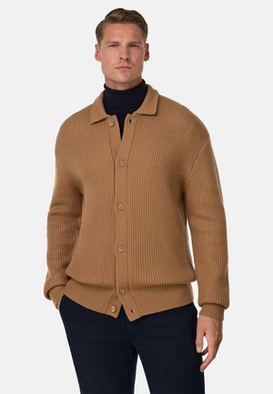 Bruine geribbelde cardigan met een kraag, knoopsluiting en lange mouwen, gedragen over een donkere turtleneck. Gladde textuur en relaxte pasvorm.