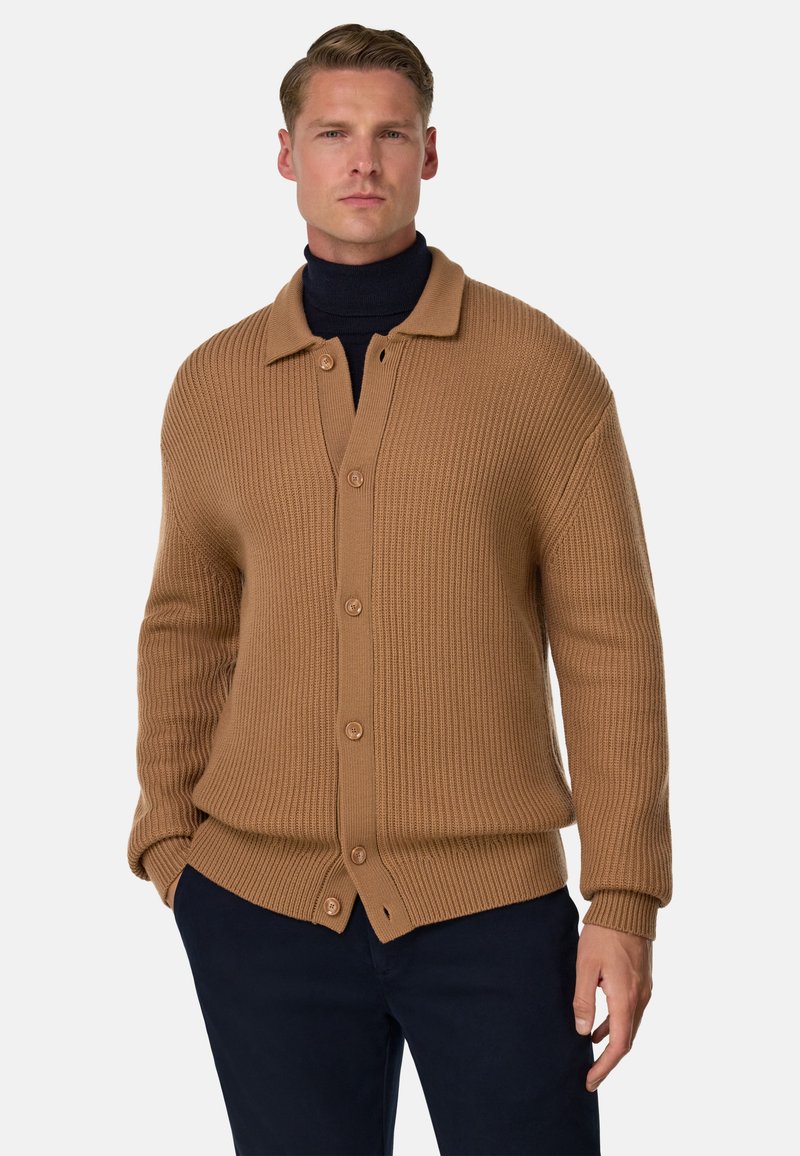 Bruine geribbelde cardigan met een kraag, knoopsluiting en lange mouwen, gedragen over een donkere turtleneck. Gladde textuur en relaxte pasvorm.