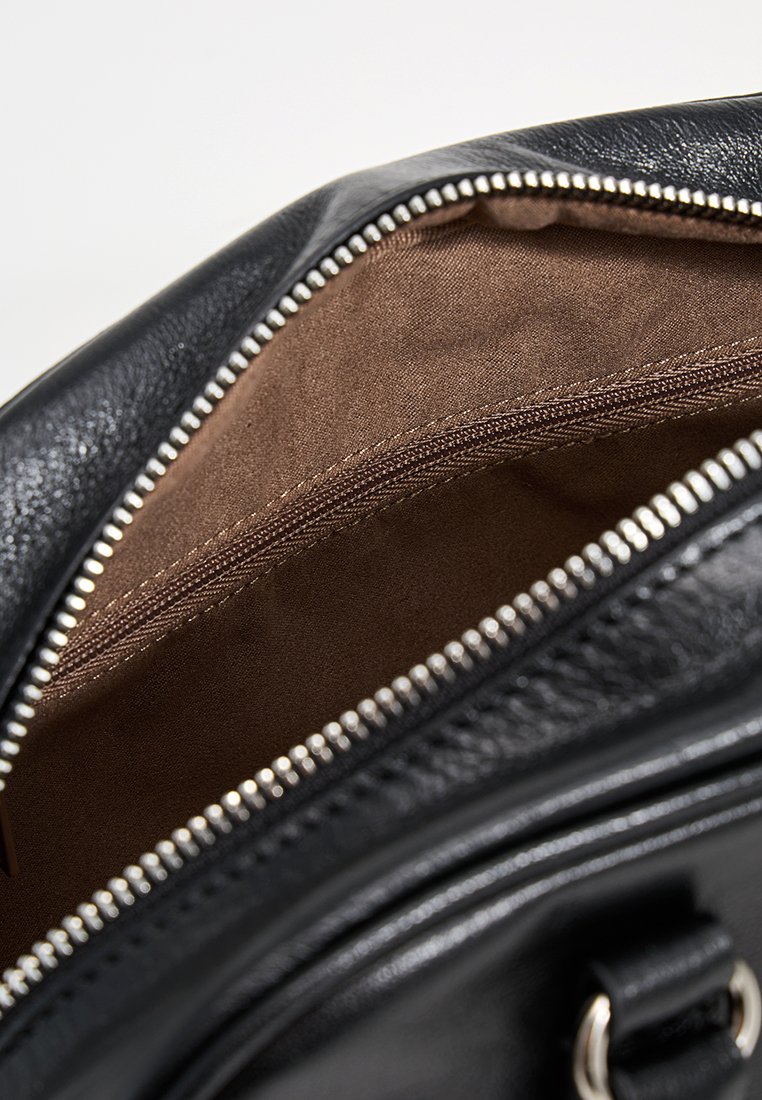 Das Innere einer schwarzen Lederhandtasche mit braunem Stofffutter und einer Reißverschlusstasche. Der Reißverschlussrand ist silberfarben und erhöht die Haltbarkeit.