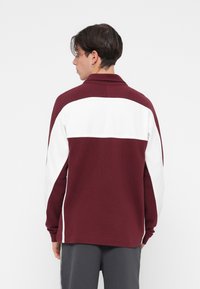 Polo de manga longa em blocos de cor em marrom e branco, com colarinho. Tecido macio, corte relaxado e faixa branca contrastante na parte superior das costas.