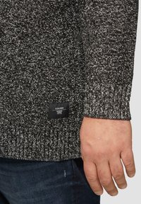 Dunkelgrauer Strickpullover mit strukturiertem Muster. Verfügt über einen gerippten Bund und Saum. Enthält ein schwarzes Markenetikett auf der unteren linken Seite.