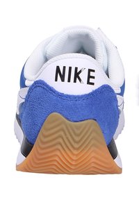 Sneaker Nike avec un empeigne en suède bleu et en mesh blanc, accents noirs, et une semelle en caoutchouc gommé texturé avec des motifs ondulés.