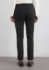 Schwarze maßgeschneiderte Hose mit geradem Bein, mittlerer Bundhöhe, Rückentaschen mit Knöpfen und einer glatten Stofftextur.