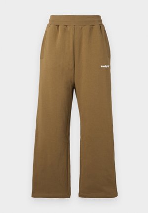 Pantalon de survêtement marron à jambes larges avec ceinture élastique, poches latérales et petit logo blanc "lowlights" sur la cuisse droite.