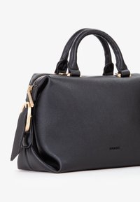 Sort læderhåndtaske med en pebberet tekstur, dobbelt håndtag, hardware i guld tone og et sidelabel. Lynlås lukning langs toppen.