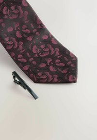 Hedvábná kravata s čiernym pozadím a tmavočerveným kvetinovým vzorom. Súčasťou je aj čierna kravata na klip s elegantným dizajnom.