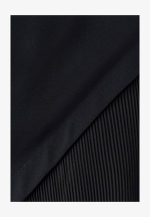 Tissu noir présentant des zones lisses et texturées ; un côté est en matériau satiné uni, tandis que l'autre montre des plis verticaux.