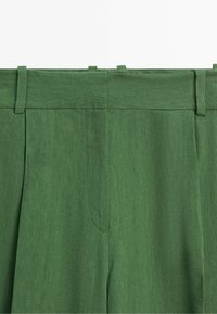 Groene broek met hoge taille, riemlussen en een voornaaddetail, gemaakt van gestructureerde stof.