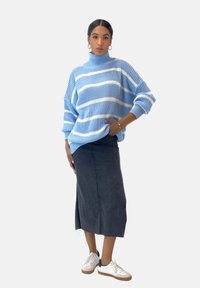 Hellblauer, gestrickter Rollkragenpullover mit weißen Streifen, kombiniert mit einem schwarzen Denim-Midirock und weißen Sneakers mit braunen Sohlen.