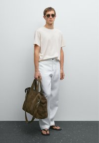 Light beige t-shirt, white wide-leg trousers, brown suede bag with silver hardware, and black flip-flops. Accessories include dark sunglasses.