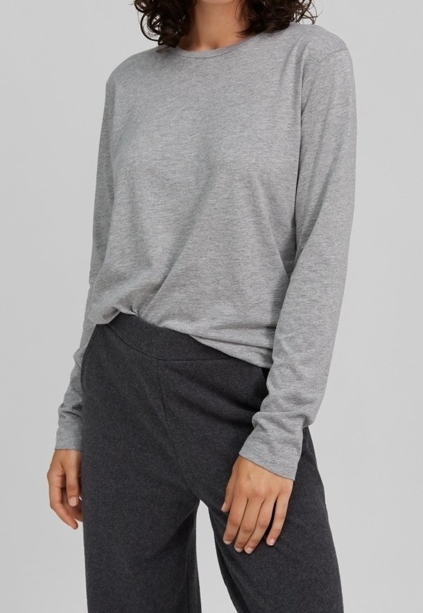 Graues Langarmshirt aus weichem Stoff, mit Rundhalsausschnitt und lockerer Passform, kombiniert mit dunkelgrauen, weiten Hosen.