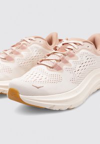 Zapatillas de running ligeras en blanco y rosa suave, con parte superior de malla, diseño estampado y una suela de goma texturizada para tracción.