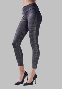 Leggings a vita alta, neri e con motivo metallico, caratterizzati da una texture liscia e un design aderente, abbinati a scarpe con tacco alto nere.