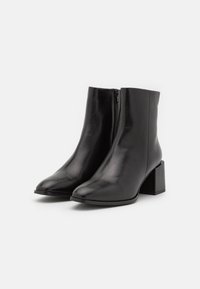 Black leather ankle boots with a pointed toe and block heel. Features a zipper closure on the side and a smooth, shiny texture.