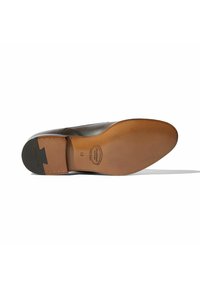 Suola di scarpe in pelle marrone con finitura liscia, forma arrotondata e tono chiaro sotto il piede. Presenta marchio e rivetti metallici vicino al tallone.