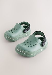 Groene klompen met een gladde afwerking, voorzien van perforaties voor ademend vermogen en een zwarte band. "BAKER" logo aan de zijkant. Ronde neusontwerp.