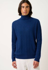 Marineblaues Rollkragensweater mit geripptem Design, das eine figurbetonte Passform und lange Ärmel aufweist. Weicher Stoff mit dezentem Zopfmuster.