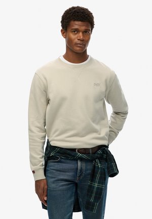 Light gray sweatshirt with a crew neck and ribbed cuffs, paired with blue jeans. A green and black flannel shirt is tied at the waist.