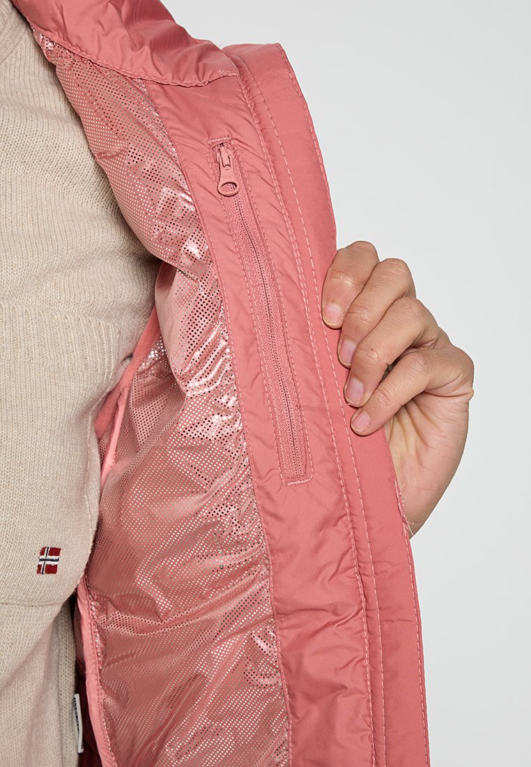 Interno di una giacca isolata rosa chiaro con fodera in rete, tasca con zip e cuciture a contrasto, mostrata mentre viene tenuta con un maglione beige sotto.