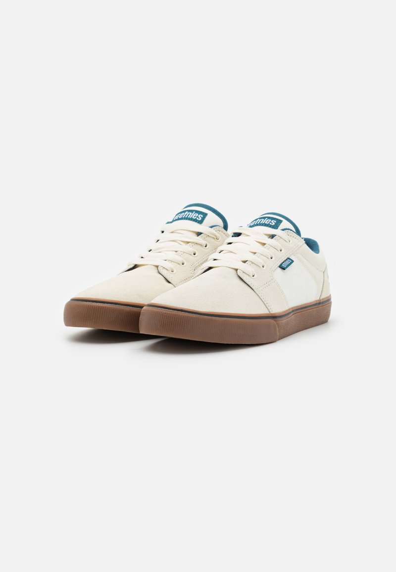 Beige Leinensneaker mit hellbraunen Gummisohlen, versehen mit blauen Akzenten und Schnürverschluss. Entworfen mit einem gepolsterten Kragen für zusätzlichen Komfort.
