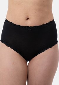 Donna che indossa biancheria intima nera di cotone a vita alta con pizzo e un piccolo fiocco frontale, mostrando la parte centrale del corpo e le cosce superiori su uno sfondo bianco.
