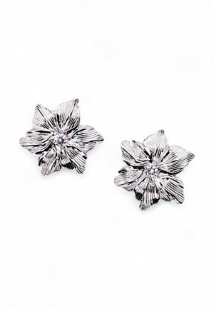 Orecchini argento a forma di fiore con petali testurizzati e una pietra preziosa centrale trasparente. Il design presenta linee intricate e profondità.