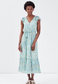 Robe maxi florale avec décolleté en V, manches courtes volantées et taille élastique avec ceinture à nouer. Couleur : vert menthe avec des fleurs orange.